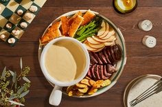 a plate with potatoes, asparagus and other food on it next to a cup of coffee