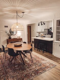 a dining room table with chairs and a rug on the floor in front of it