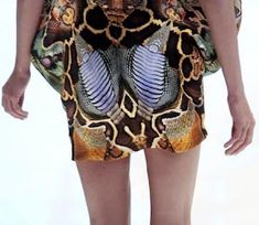 a woman is walking down the runway wearing a dress with an animal print on it