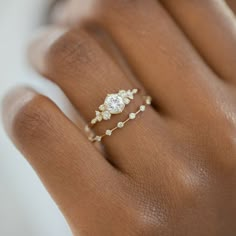 a woman's hand with a diamond ring on top of her finger and the other hand holding it