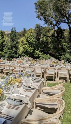 tables and chairs are set up for an outdoor dinner in the grass with flowers on them