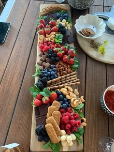 a wooden table topped with lots of fruit and crackers on top of each other