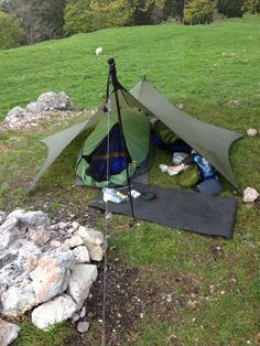 a tent is set up in the grass with its door open and it's contents laid out