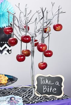 a table topped with an apple tree next to a sign that says take a bite