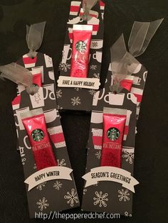 four starbucks products wrapped in black and white paper with red ribbon on them, sitting inside small packages