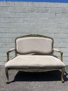 an old fashioned couch sitting in front of a brick wall with no one around it