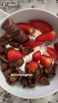 a white bowl filled with chocolate covered strawberries and cereals next to a spoon