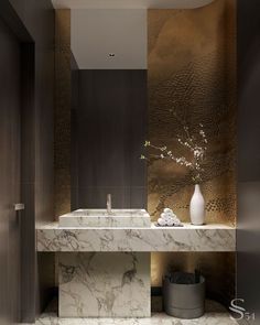 a bathroom with marble counter tops and gold foiled wallpaper on the walls, along with a white vase filled with flowers