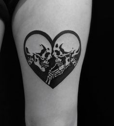 a woman's thigh with two skulls in the shape of a heart on it