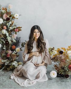 a pregnant woman sitting in front of flowers