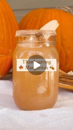 a jar filled with liquid sitting on top of a table next to two pumpkins