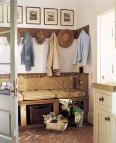 a room with a bench, coat rack and pictures on the wall