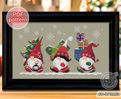 three christmas gnomes with presents on their heads cross stitch pattern in a black frame