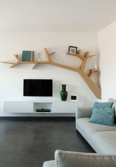 a living room with a couch, television and shelves on the wall above it's entertainment center