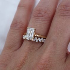 a woman's hand with a diamond ring on top of her finger and an engagement band