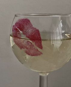 a wine glass filled with white wine and red lipstick