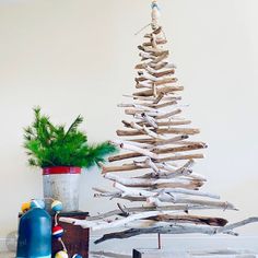 a wooden christmas tree sitting on top of a table next to a potted plant