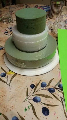 a green cake sitting on top of a table next to a piece of paper and scissors