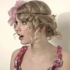 a woman with blonde hair wearing a pink flower in her hair and a headband