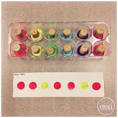 a plastic container filled with different colored cupcakes next to a white paper sheet