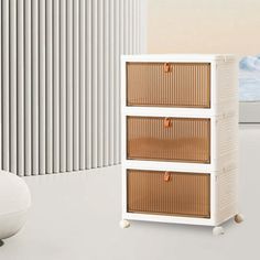 a white cabinet with three drawers next to a chair