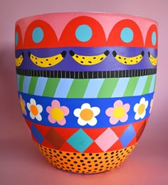 a brightly colored vase is sitting on a pink surface with polka dots, circles and flowers