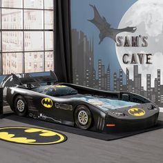 a batman car bed is shown in front of a window with the moon behind it