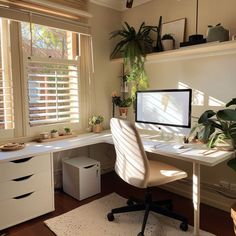 a desk with a computer on top of it next to a window covered in blinds