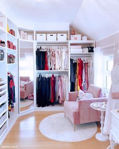 an organized closet with clothes on hangers, and a pink chair in the corner