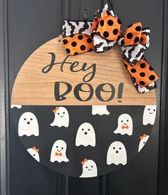 a door hanger decorated with black and orange polka dots, ghost faces and the words hey boo on it