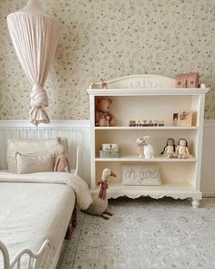 a white bed sitting next to a book shelf filled with books and stuffed animals on top of it