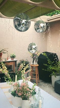 an outdoor party with disco balls hanging from the ceiling and flowers in vases on the table