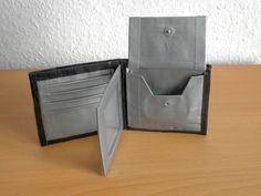 an open wallet sitting on top of a wooden table next to a card holder with two cards in it