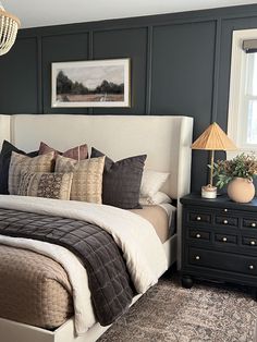 a bedroom with a bed, nightstands and rug on the wooden floor next to two windows