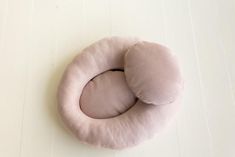 two pink pillows sitting on top of a white floor next to each other and one is in the shape of a circle