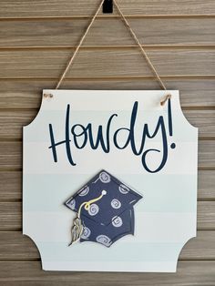 a sign hanging on the side of a building that says, hoddyy with a graduation cap and tassel