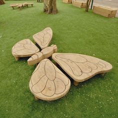 wooden benches sitting on top of green grass next to a tree in the middle of a park