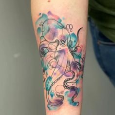 an octopus tattoo on the arm with watercolor paint splatters and bubbles around it