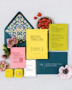 the wedding stationery is laid out on top of each other with flowers and candy