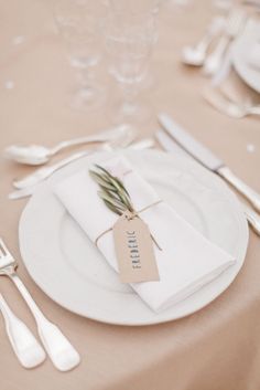 a white plate topped with a tag next to silverware and utensils on top of a table