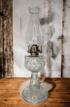 an old fashioned oil lamp sitting on top of a wooden table