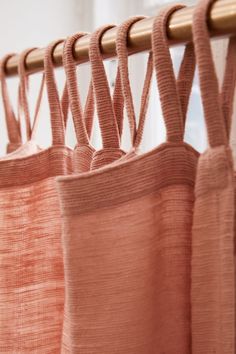 some pink curtains hanging from a wooden rod