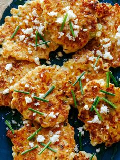 some food is on a blue plate with green sprinkles and feta cheese