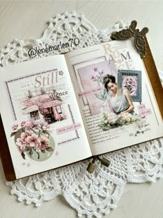 an open book sitting on top of a table next to a lace doily with flowers