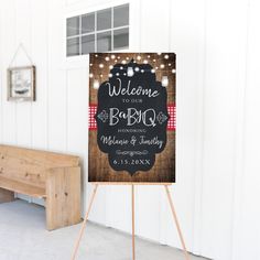 a welcome sign with lights on it in front of a white wall and wooden bench