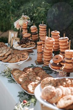 a table topped with lots of donuts covered in frosting next to other desserts