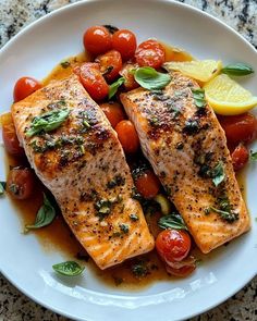 two salmon fillets with tomatoes and herbs on a white plate