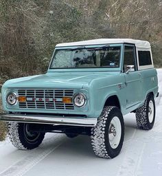 an old blue truck is parked in the snow