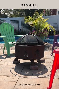 A black lift off dome outdoor fire pit screen mounted on a metal fire bowl situated on apatio near the pool  surrounded by colorful chairs