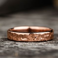 a rose gold wedding band on top of a piece of wood